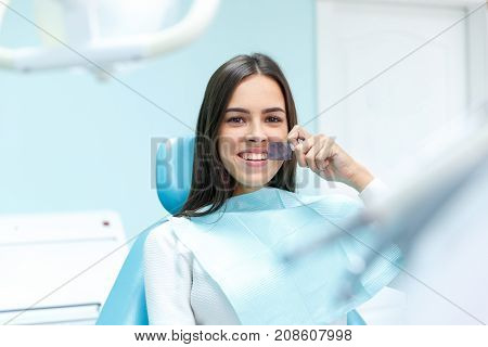 Happy long-haired girl in stomatology policlinic. A girl sits in the dentist's room and pleased with the service. Close-up of girl. Medical concept.