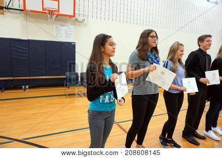 JOLIET, ILLINOIS / UNITED STATES - MAY 11, 2016: Eighth grade students proudly hold certificates of awards that they have earned, in the gymnasium of the Drauden Point Middle School.