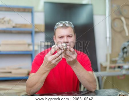 Master in red uniform with various tools collects a wooden car model