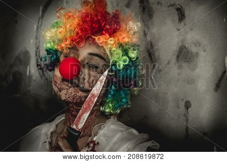Asian girl dress killer joker to Halloween festival She holds a knif soaked with blood with scary eyes ready to kill people.