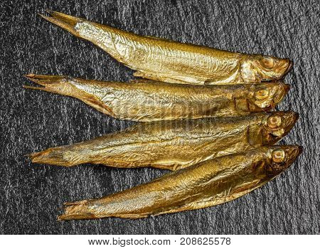 arrangement with fresh smoked sprats on dark stone slab