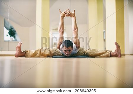 A young strong man doing yoga exercises -Samakonasana Straight angle pose in the yoga studio.