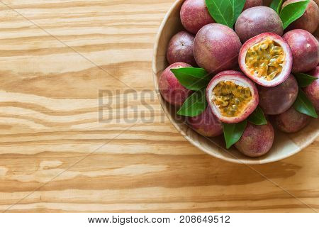 Fresh passion fruit in wood bowl on wood table in top view flat lay with copy space for background or wallpaper. Ripe passion fruit so sweet and sour. Passion fruit is tropical fruit. Passion fruit background concept.
