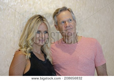 Image of a mature man and beautiful woman glancing away from camera