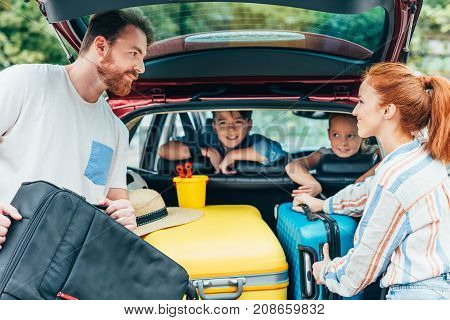 Family Packing Luggage In Trunk