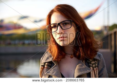 Portrait of Beauty Teenage Model Girl with Red Hair on the Background of Nature on the Field in Sun Light. Face of Young Woman with Freckles. Autumn. Glow Sun Sunshine. Backlit. Warm Color Tones