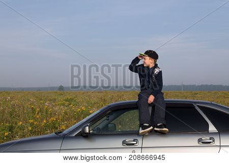 Ekaterinburg, Russia - August 28, 2017: Nikita Dorokhin (8 years old) from Nizhny Tagil, sits on the roof of Lada Priora and looks into the distance