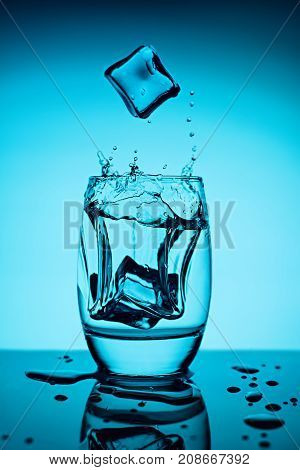Water splash in glass with ice cubes.