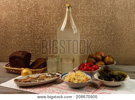 Ukrainian National Drink And Snack. The Big Bottle And Glass Of Moonshine On The Old Wooden Table