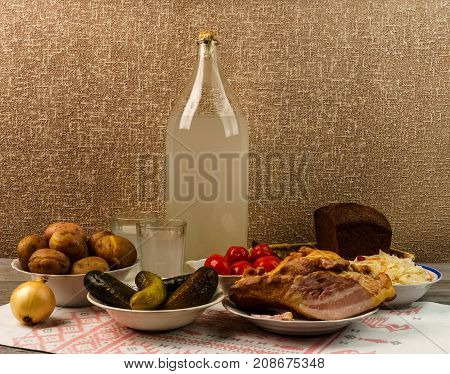 Ukrainian National Drink And Snack. The Big Bottle And Glass Of Moonshine On The Old Wooden Table