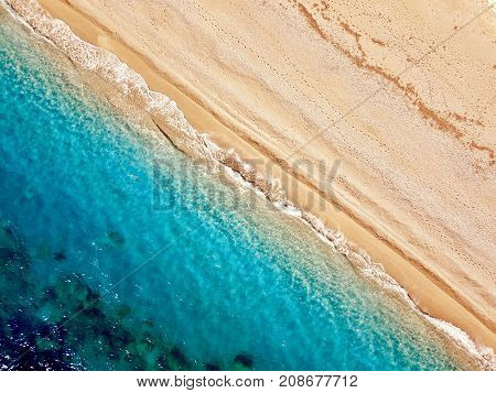 Top view of a deserted beach. The greek coast of the Ionian Sea. Aerial photo of sea waves reaching shore.