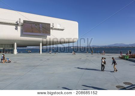 SANTANDER SPAIN - OCTOBER 7 2017: Tourists and local citizens stroll on the promenade near the Centro Botin. The building was designed by Italian architect Renzo Piano.