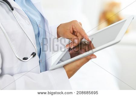 Woman doctor using tablet computer while standing straight in hospital.
