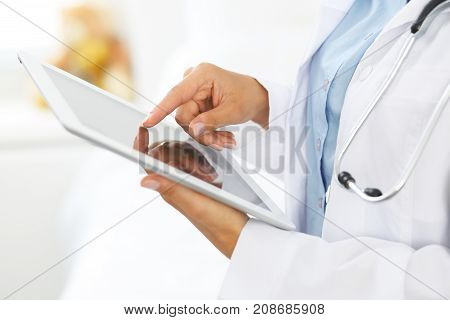Woman doctor using tablet computer while standing straight in hospital.