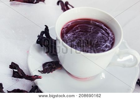 white porcelain mug with tea karkade on white tulle