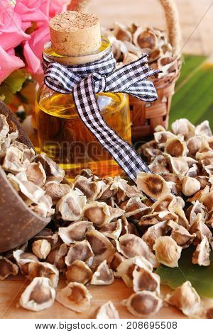 Moringa oleifera oil and seeds on wood background
