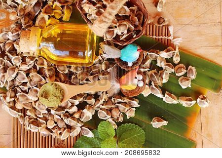 Moringa oleifera oil and seeds on wood background