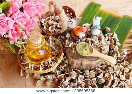 Moringa oleifera oil and seeds on wood background