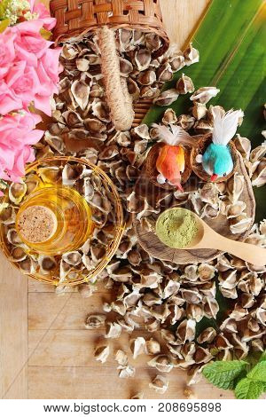 Moringa oleifera oil and seeds on wood background