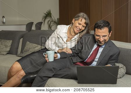 Couple At Home In Formalware With Man Working And Woman Watching Over His Shoulder