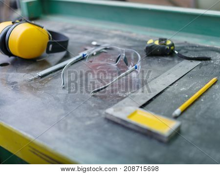 Tools of the carpenter close-up on a gray background of the table calliper, roulette, glasses, corner, pencil