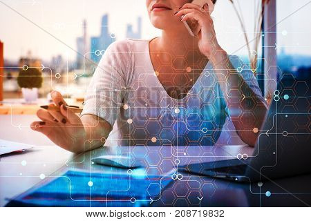Businesswoman talking on the phone at office desk with laptop and digital circuit pattern. Blurry city background. Network concept. Double exposure