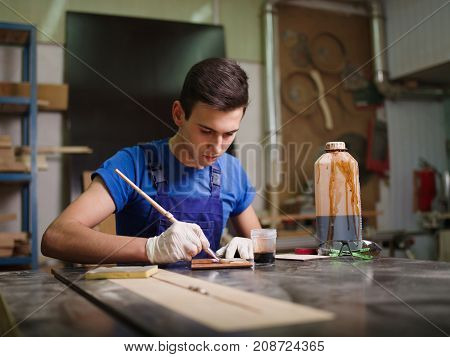 A wooden plate, on which the imprint of the paw imprinted patterns and inscriptions, the master began to apply the varnish close-up