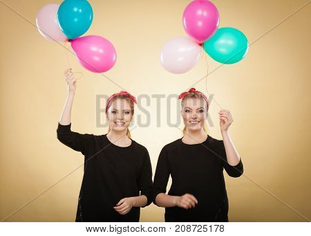 Memory of childhood and forgotten dreams. Two cute lovely retro styled women behave like little girls. Adults trying to fly away by balloons to dream come true.