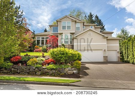 House with green lawn manicured frontyard garden in suburban residential neighborhood on a sunny day