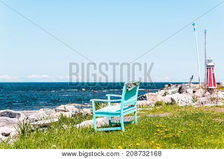 One Peaceful Blue Aquamarine Turquoise Green Beach Chair Empty Bench In Front Of Ocean With Red Ligh