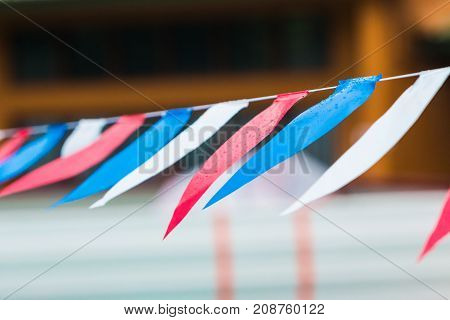 section of wet string flags in red blue and white colors hanging outdoor in the rain with slight blown wind