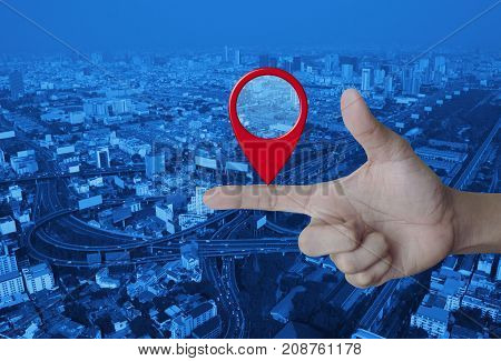 Map pin location button on finger over modern city tower street and expressway Map pointer navigation concept