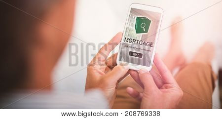 Digital image of mortgage text with icon and bedroom against man using mobile phone in living room