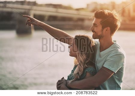 Young couple embracing while watching the sunset over the city.
