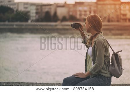 Image of young beautiful woman photographing outdoor.