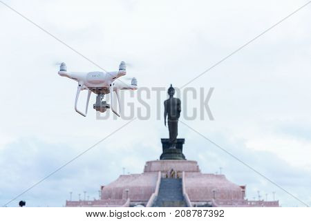 An unmanned aerial vehicle (UAV) or drone flying in the air with Phutthamonthon Isan background Thailand