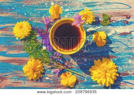 yellow сup with tea or coffee multicolor flowers around