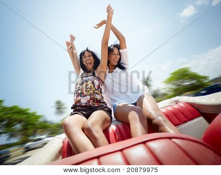 Dos hermanas gemelas hermosas divirtiéndose en coche descapotable
