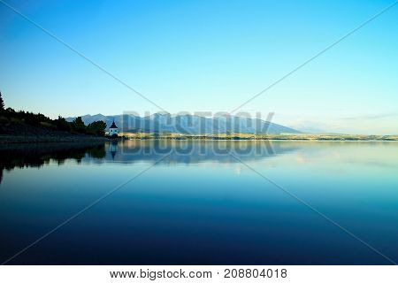 View on level water in dam Liptovska Mara with the background of the Havranok church. Water reservoir on Liptov. Beautiful Slovak scenery.