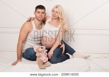 Beautiful pregnant couple in love on the background. Hands of husband on the tummy of his pregnant wife. Young man tenderly stroked pregnant belly of his wife. Husband kissing pregnant belly.