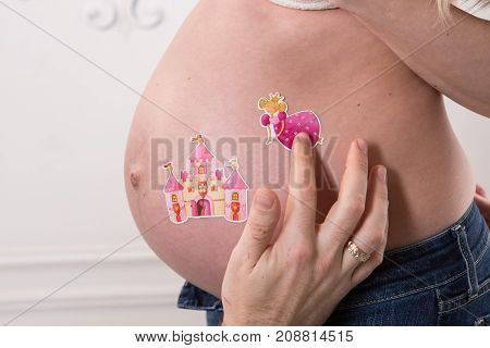 Beautiful pregnant couple in love on the background. Hands of husband on the tummy of his pregnant wife. Young man tenderly stroked pregnant belly of his wife. Husband kissing pregnant belly.