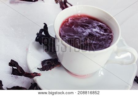 white porcelain mug with tea karkade on white tulle
