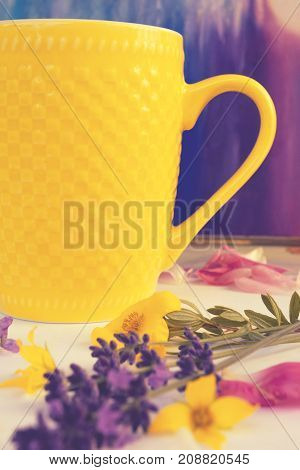 yellow сup with tea or coffee multicolor flowers around