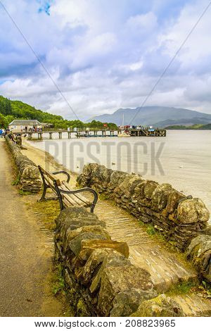 Bench and rock wall on the shore of Loch Lomond in Luss, Scotland