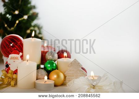 Festive Christmas decorations with candles ornaments and Chirstmas tree with copyspace on white
