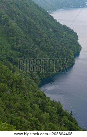 Green slopes surrounding the beautiful and deep blue Lake Mashu, Hokkaido, Japan