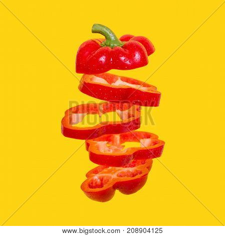 Creative concept with Flying red capsicum. Sliced floating bell pepper on an orange background. Levity vegetable. Paprika with water drops
