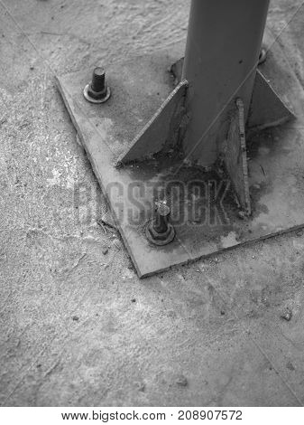 BLACK AND WHITE PHOTO OF SCREWS AND NUTS ON LAMP POST CONCRETE BASE