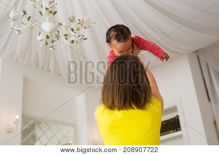happy family. Mother throws up baby, playing at home.