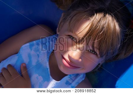 Smiling girl having fun on children's slide. A ray of sunlight passes over her face.